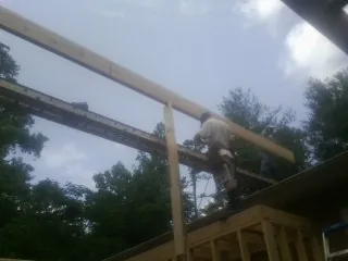 Carpenter setting a ridge beam over a new addition frame — Ice Dam Removal by Roofing Brothers in Mc Connells