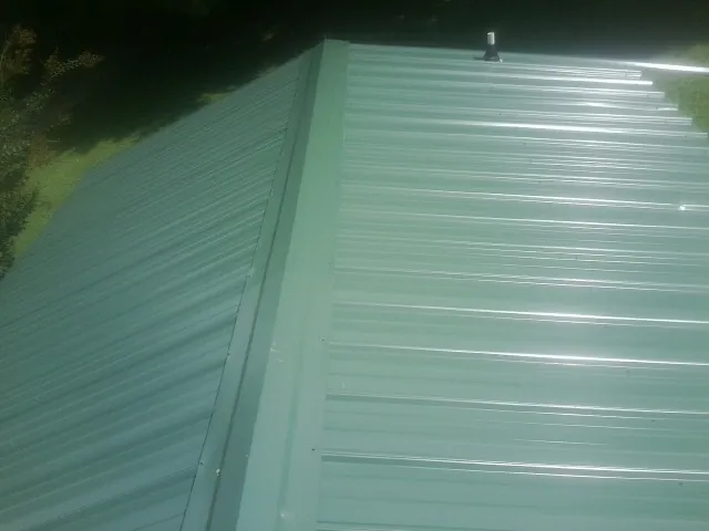 New green metal panels meeting at the ridge of a roof — Flat Roof Repair work by our crew in Mc Connells