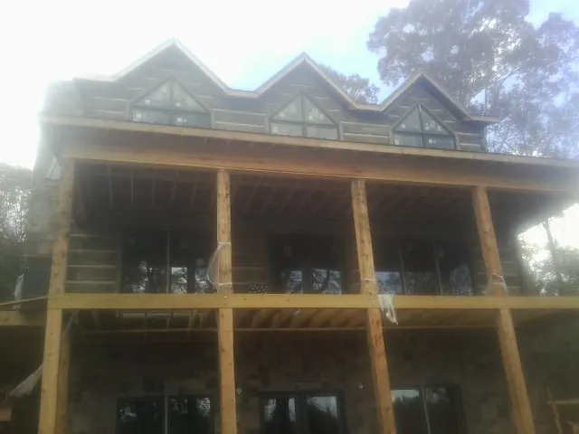 Dormers and porch framing on a large log home under construction — Roof Coating work by our crew in Mc Connells