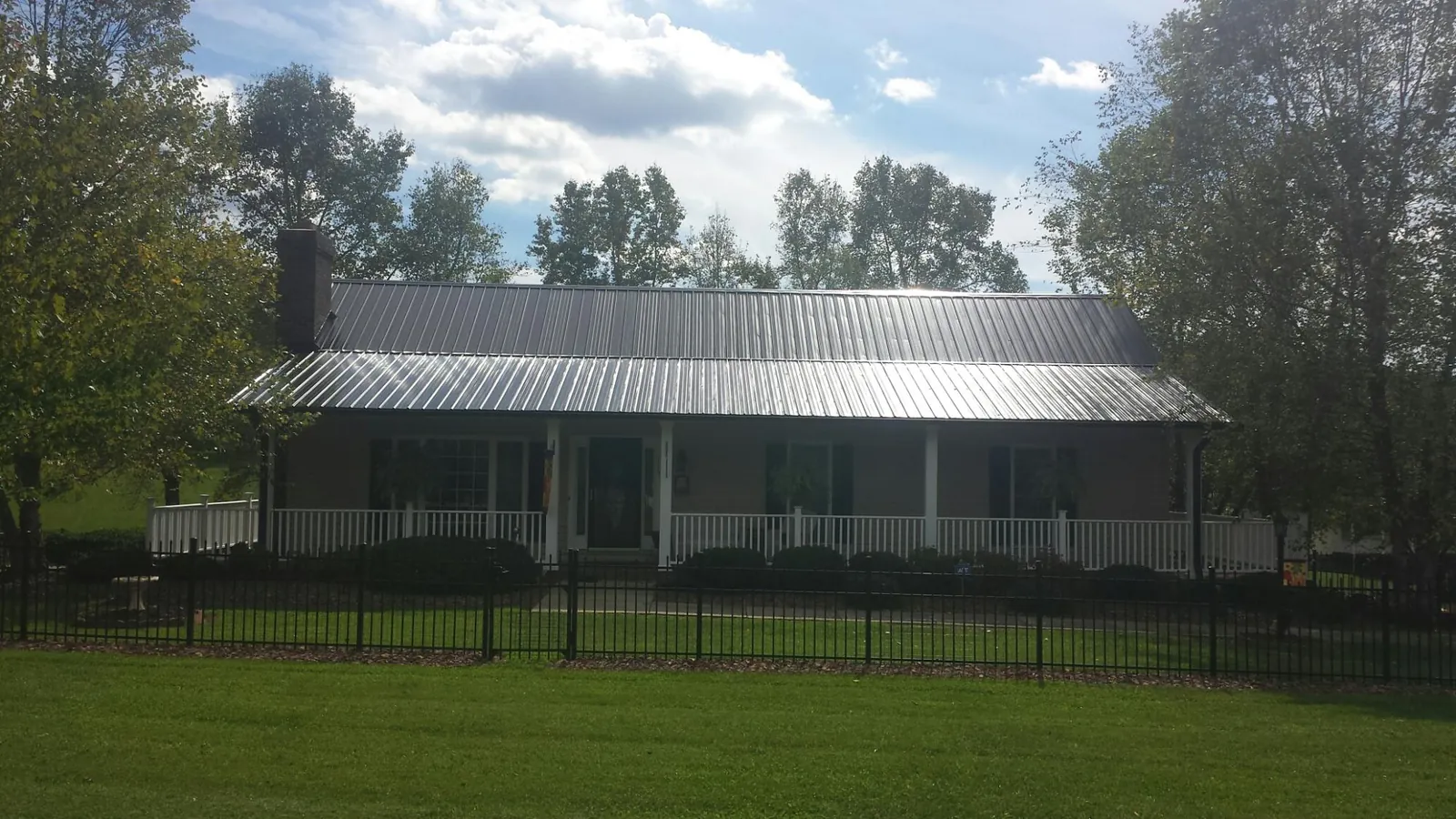 Gray metal roof on a brick ranch with a full width front porch — Gutter Guard Installation work by our crew in Mc Connells