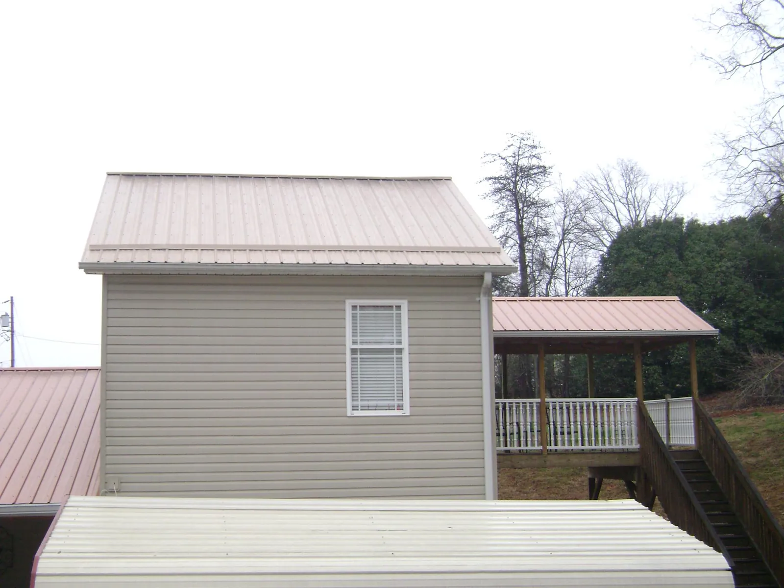 Tan metal roofs on a two story addition and attached porch, from a Roof Replacement job in Mc Connells