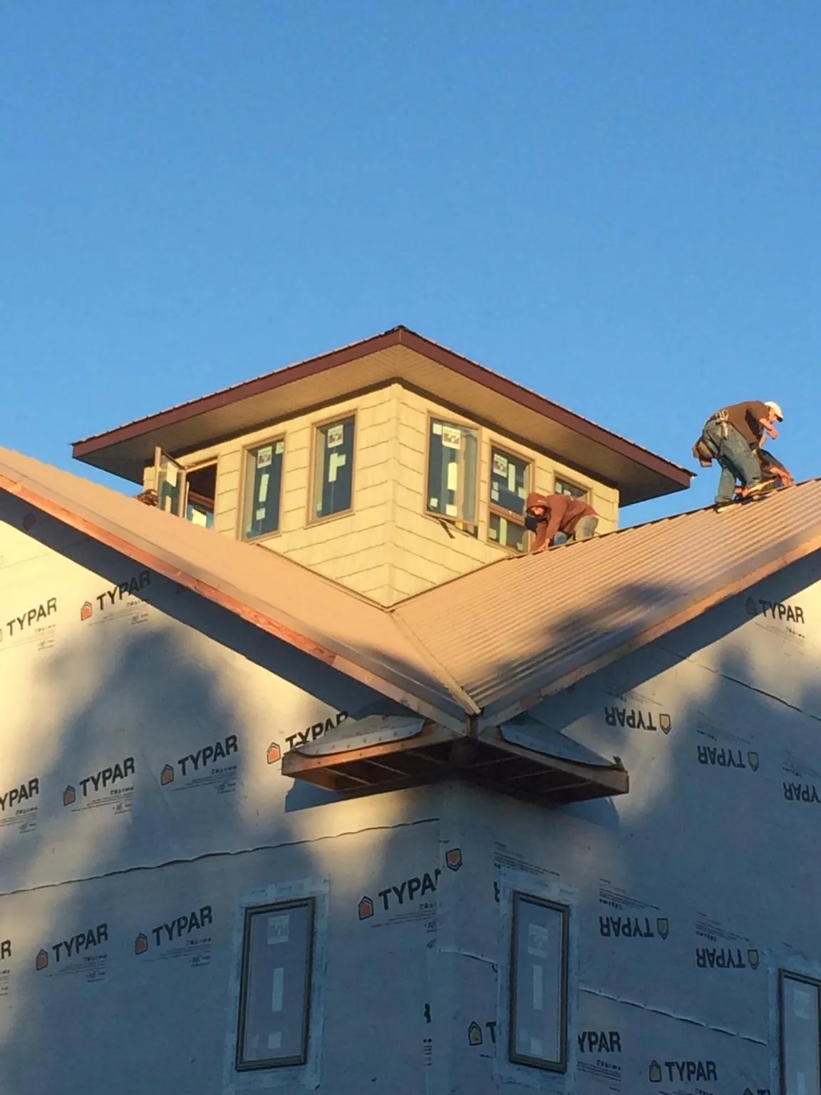 Roofers working around a rooftop cupola on a new metal roof at sunset — Roof Waterproofing in Mc Connells by Roofing Brothers